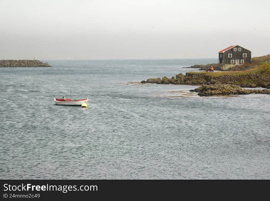 Iceland landscape with a black house, boat, and sea.