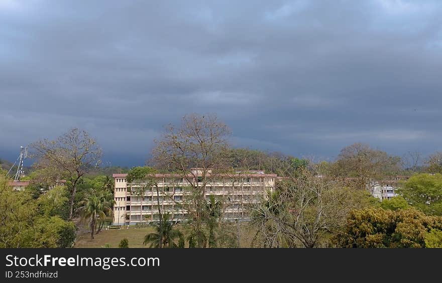 Beautiful natural reflection of white buildings and dead trees under a black sky covered with clouds