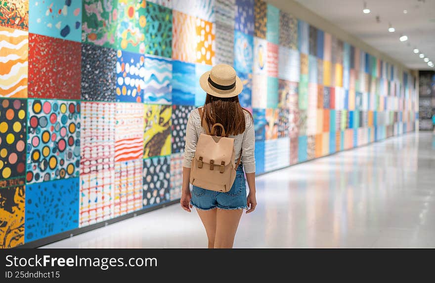 Young woman exploring a vibrant art gallery with colorful mosaic walls