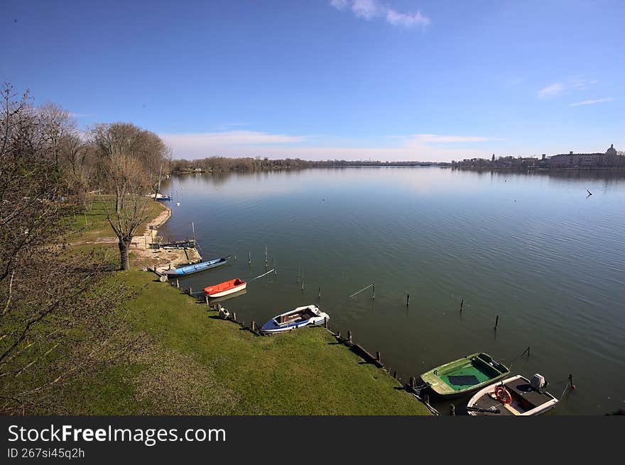 Lakeshore on a sunny day, with moored boats, and a forest stretchjing to thje horizon, seen from above. Lakeshore on a sunny day, with moored boats, and a forest stretchjing to thje horizon, seen from above