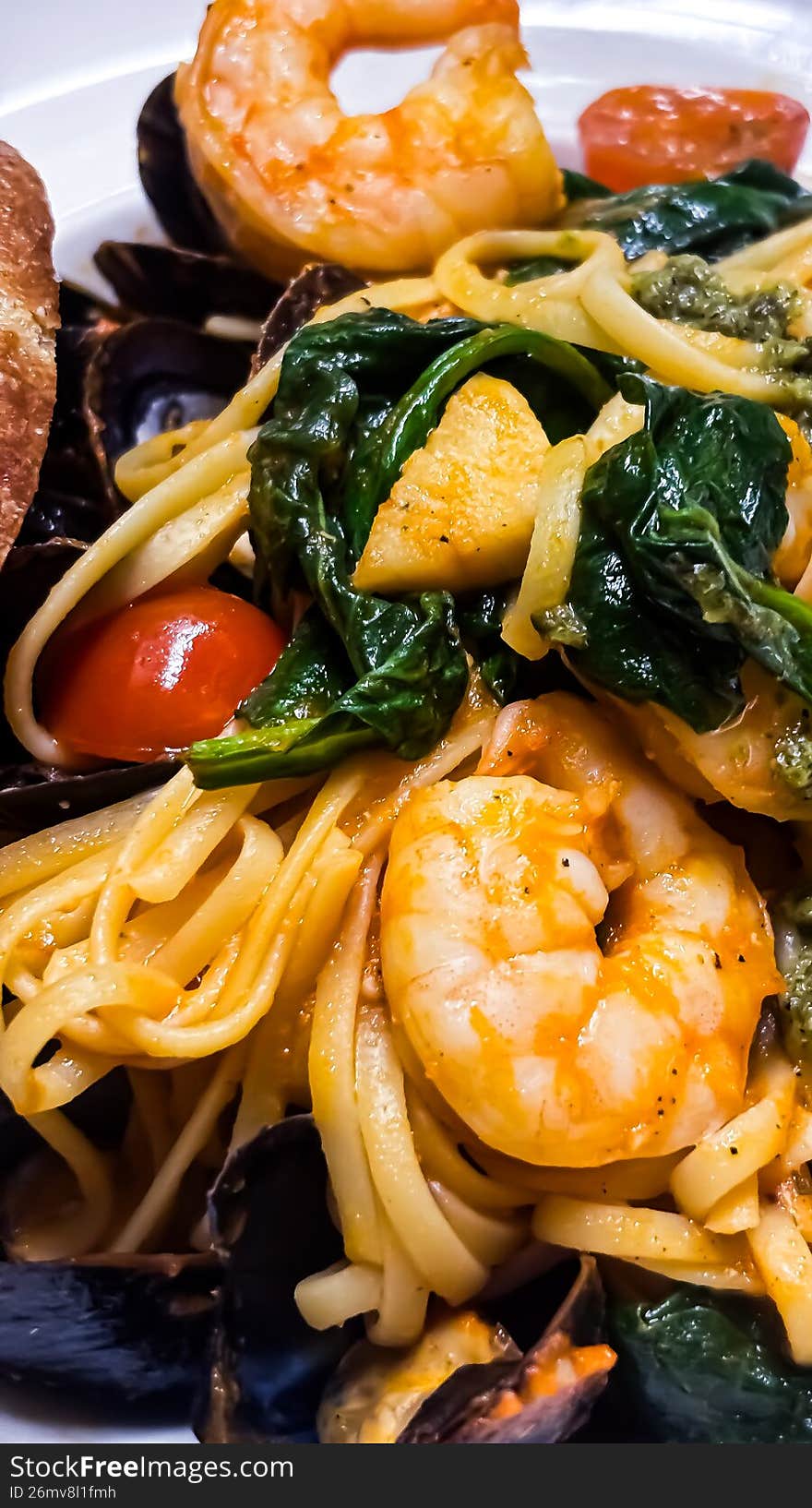 A stunning, top-down culinary shot of authentic Italian seafood linguine. Long strands of al dente pasta are tossed in a silky garlic and white wine butter sauce, featuring a premium medley of succulent prawns, fresh mussels, and clams. Garnished with cracked black pepper and finely chopped Italian parsley, this vibrant dish is presented in a shallow ceramic bowl. Ideal for Mediterranean diet features, fine dining menus, and luxury food blogs.