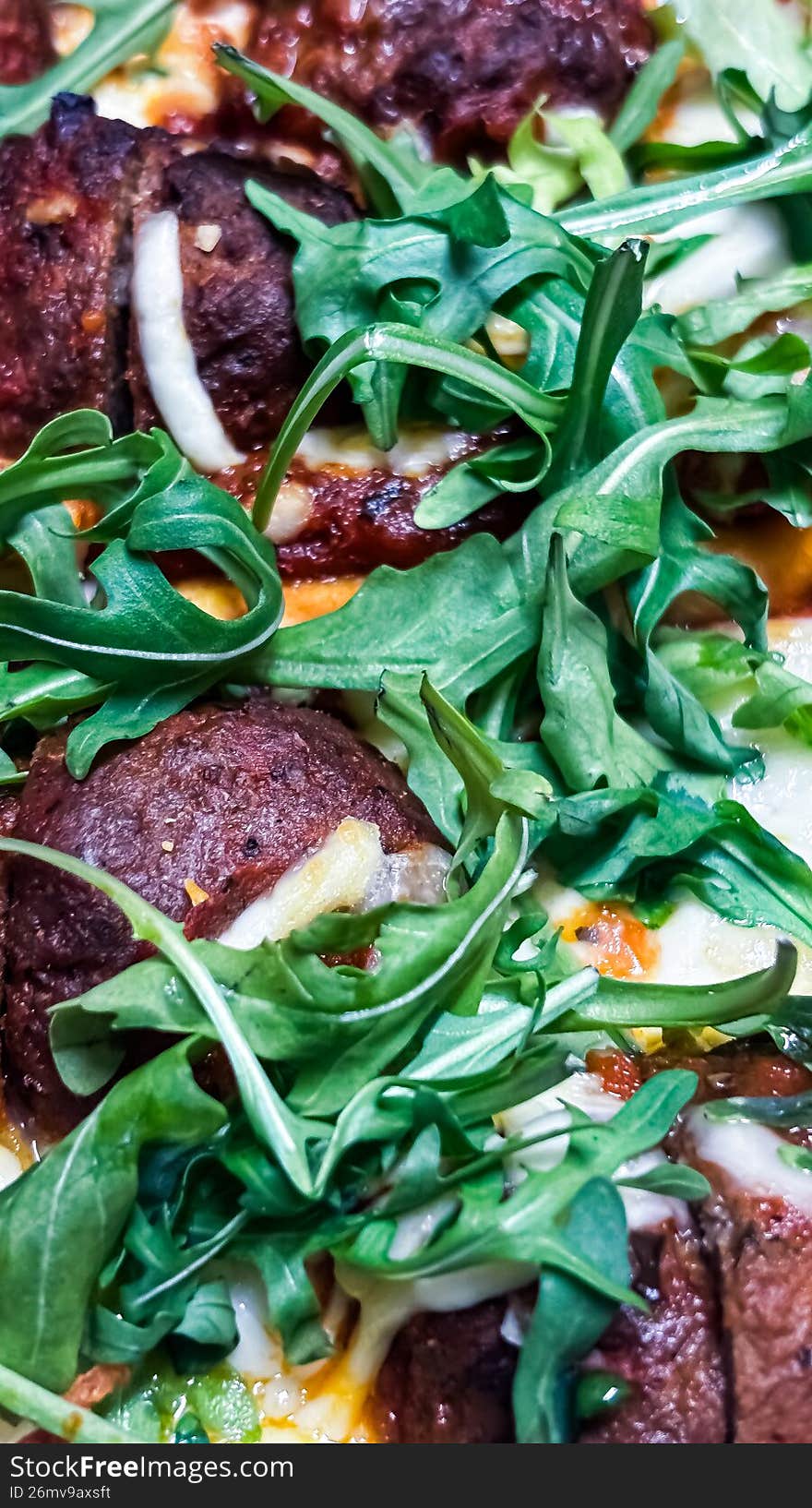 A delicious, close-up shot of a rustic thin-crust pizza topped with juicy, seasoned meatballs, melted mozzarella cheese, and vibrant fresh basil leaves. Set against a dark, moody background, this high-angle shot highlights the golden-brown crust and savory textures, making it perfect for culinary and restaurant marketing.